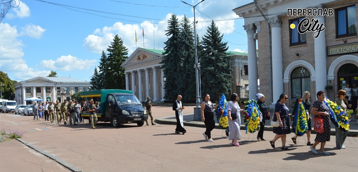 Траурна колона з Героєм "на щиті" іде площею, на якій не приспущені прапори на знак жалоби  