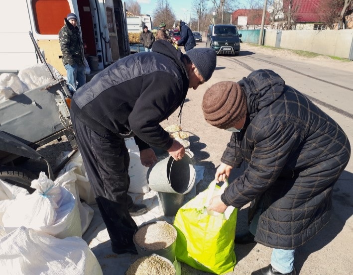 Пенсіонерка купує зерно. Вона прийшла на базар у масці