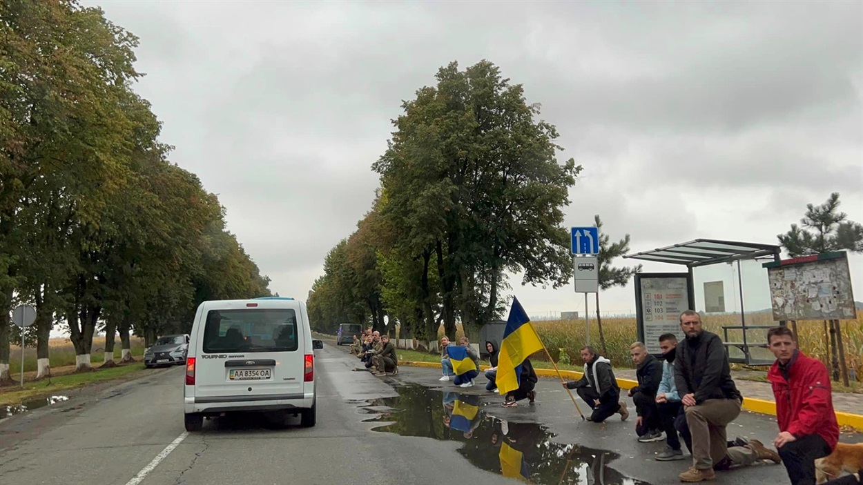 Траурну процесію героїв люди вшанували на колінах з прапорами і квітами 