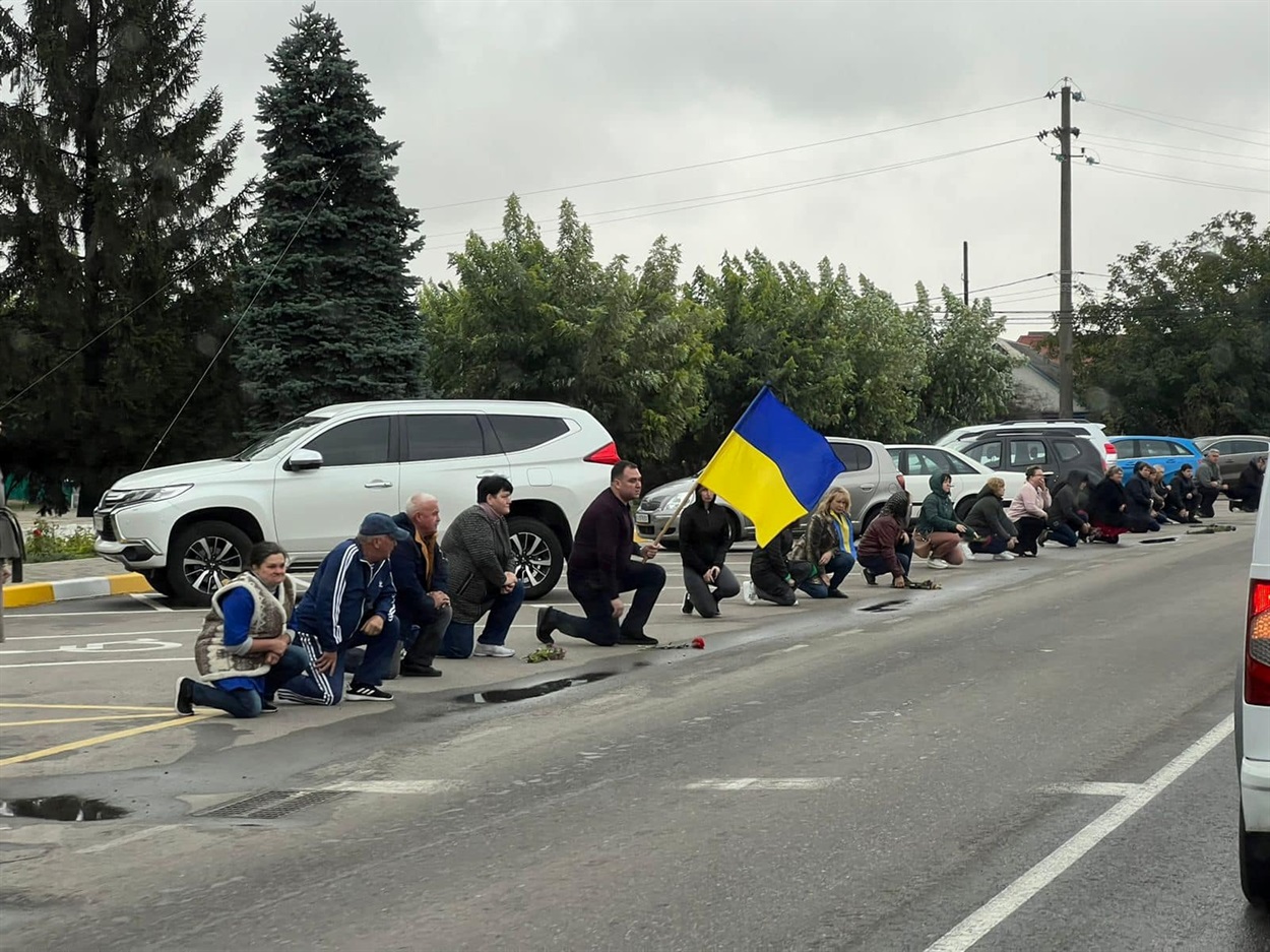 Траурну процесію героїв люди вшанували на колінах з прапорами і квітами 
