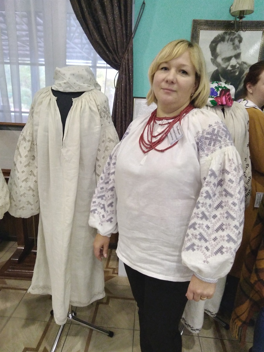 Валентина Білоусько поруч із бабусиною сорочкою. Орнамент її сорочки  вишитий за схемою бабусиної