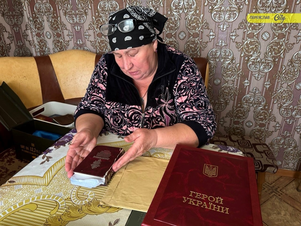 Лариса Шаповала тримає в руках синовий польовий "Молитвослов", поряд лежить нагородний футляр ордена "Золота зірка" Героя України 