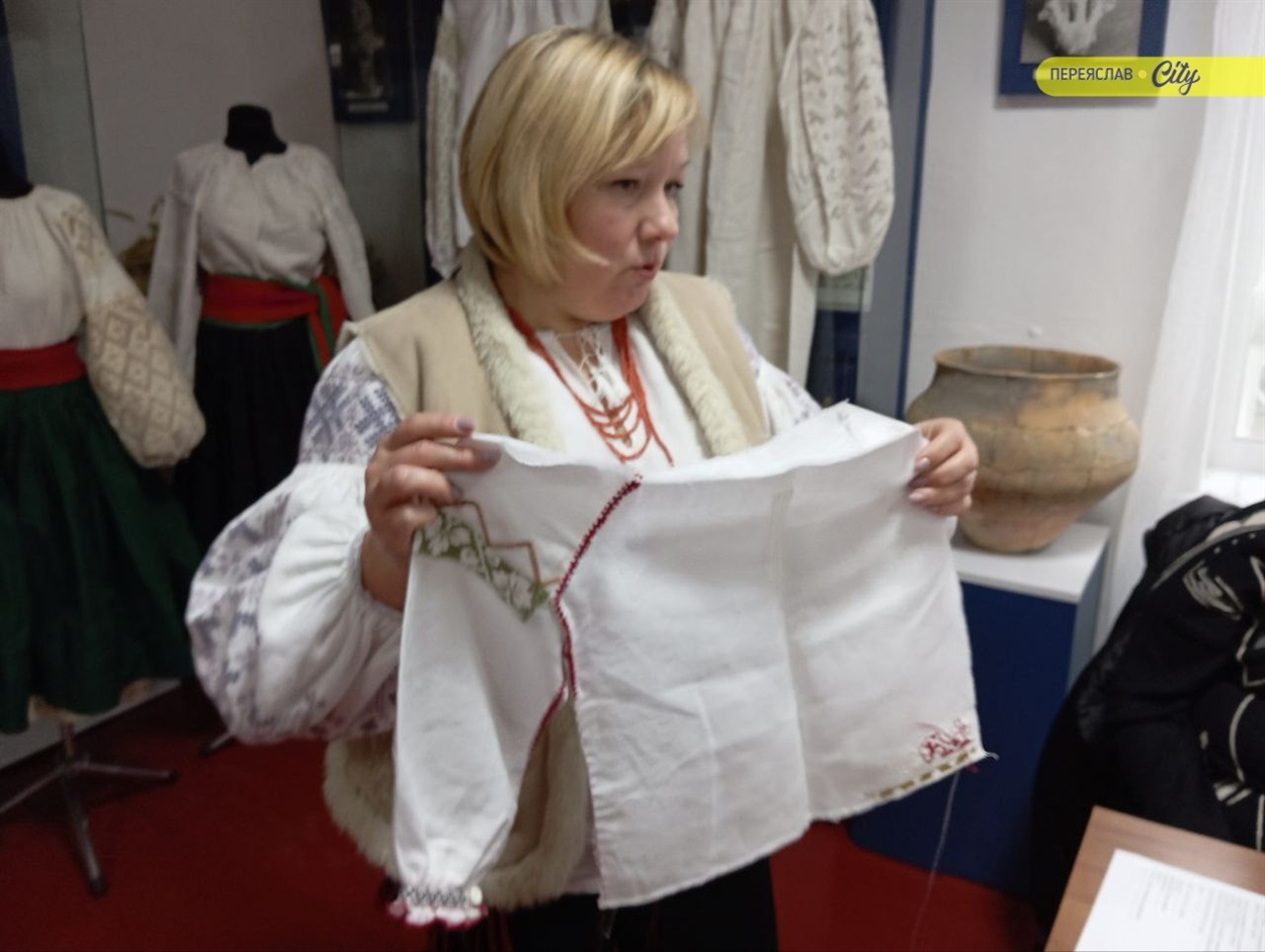 У руках пані Валентини дитяча сорочка, на ній вчаться зшивати сорочку 