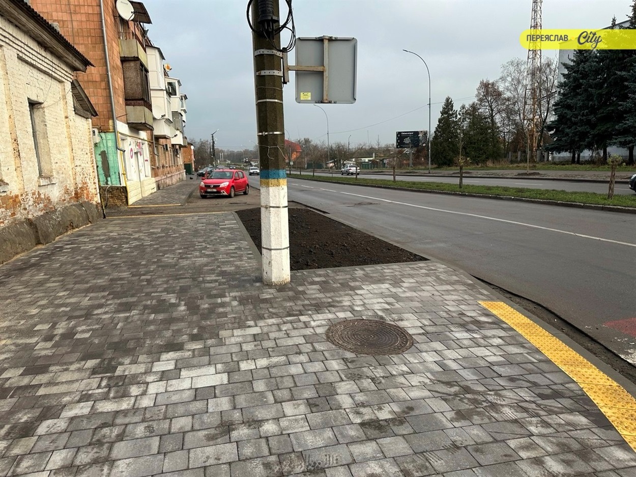 Тротуар з пологими спусками до переходу і тактильними жовтими елементами інклюзивного доступу