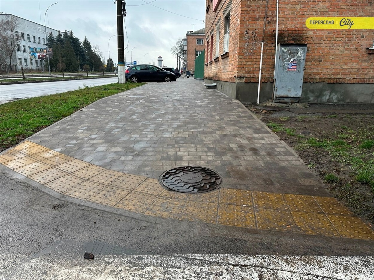 Тротуар з пологими спусками до переходу і тактильними жовтими елементами інклюзивного доступу